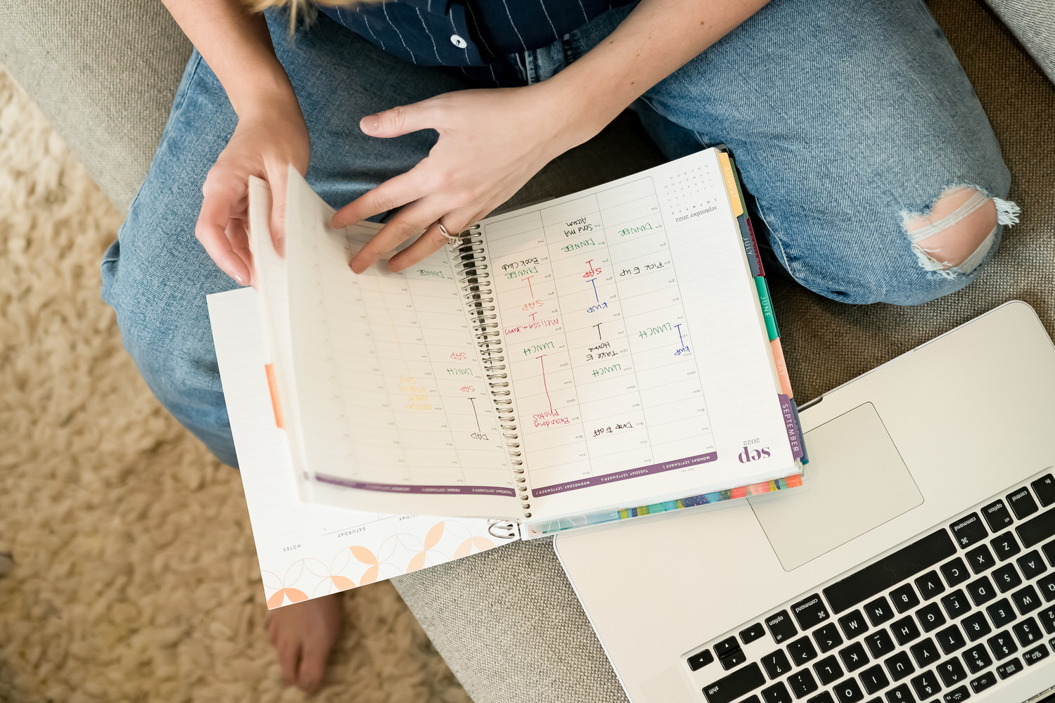 Benefits of Hiring a CRM Set-Up Specialist | Virtually Done Systems | Dubsado Set up Specialist | A picture looking down of a woman flipping the pages of a planner, a laptop visible underneath the planner. 