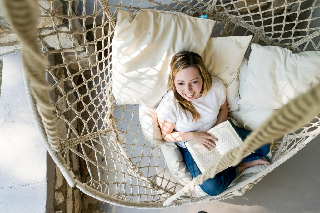 Running Your Business Without a CRM: Systems, Workflows, and Tools | Virtually Done Systems | A photo of a woman sitting in a hammock reading a book. 